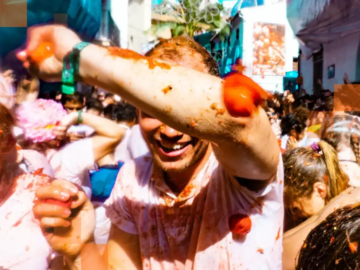 Revellers are all smiles as tomatoes are thrown in the crowded streets of Buñol. © Miles Holder